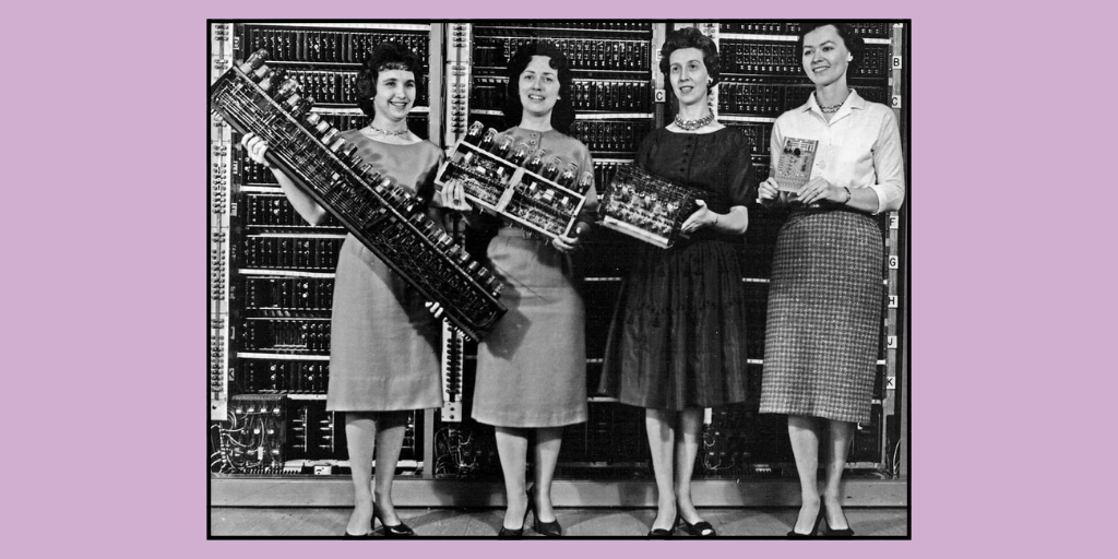 Black and white image of four of the women ENIAC Programmers, each wearing 40's-style dresses, and holding different components of the computer.
