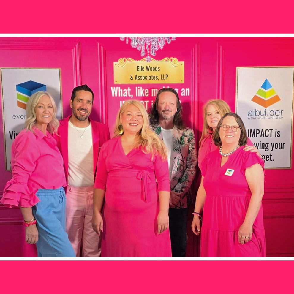 Six members of the EventBuilder team pose for a photo, they are all dressed in pink. There are three men and three women.