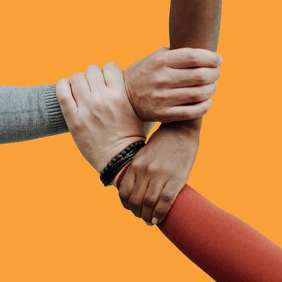 Three people's hands are centred in the image, all bracing each others wrists to make a supportive circle