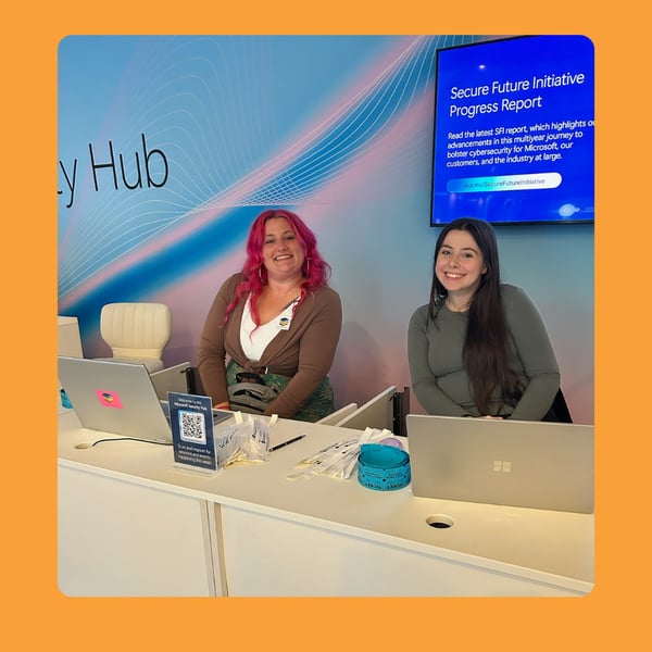 Two young women sit behind a registration desk
