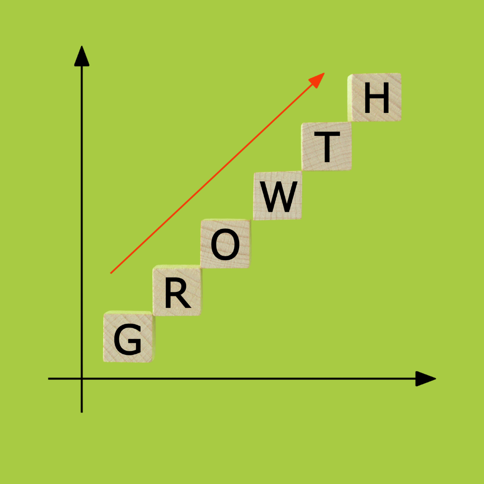 A thin black graph with wooden letter cubes spelling 'growth' moving left to right in an upwards diagonal
