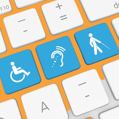 A close up of a white laptop keyboard showing three blue buttons with disability icons on them.