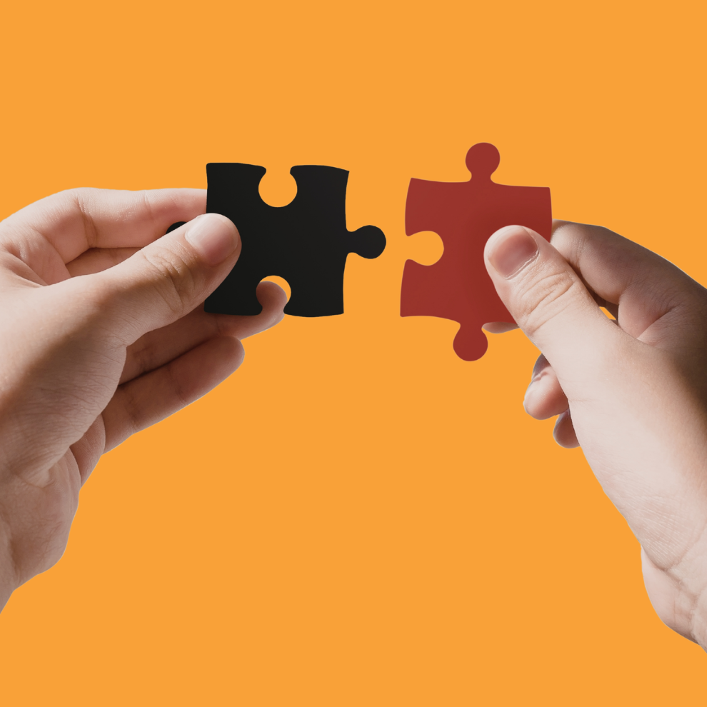 A pair of white hands holding a jigsaw piece in each hand as if to connect them