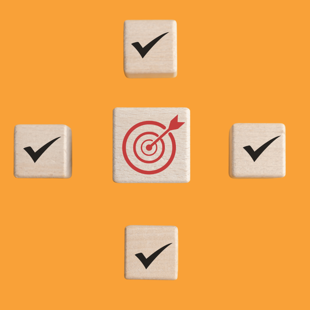 Four small wooden squares with tick marks on them surround one larger wooden block with a red arrow hitting a target