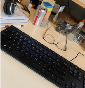 Picture of a messy desk with a keyboard in the center of the photo.